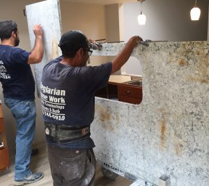 Two men are working on a counter in the kitchen.
