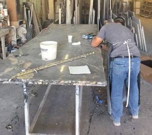 A man working on a metal table in an industrial setting.