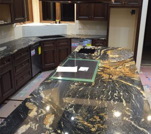 A kitchen with marble counter tops and dark wood cabinets.